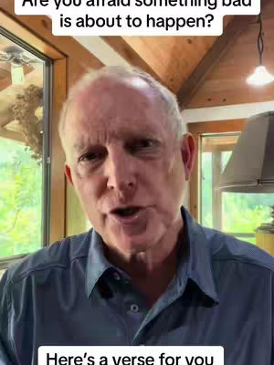 A middle-aged man with short, thinning, light-colored hair is positioned centrally. He is wearing a dark blue collared shirt and speaking directly towards the camera. The background shows a well-lit room with wooden elements and glimpses of the outdoors through a window on the left. Text is added as a hook.