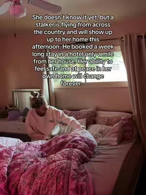 A woman is sitting on a bed, seemingly in a bedroom. The bed has a pink floral bedspread and pillows. Text overlay is added on, describing how a stalker will show up at her home. The lighting in the room is dimmed creating a sense of seriousness.