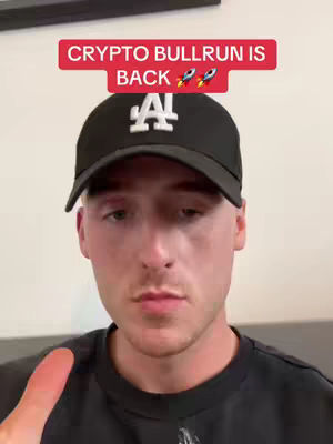 A young man wearing a black cap and a black shirt is looking at the camera, giving a thumbs up. Above his head is a red banner with the text 'CRYPTO BULLRUN IS BACK' and two rocket emojis.