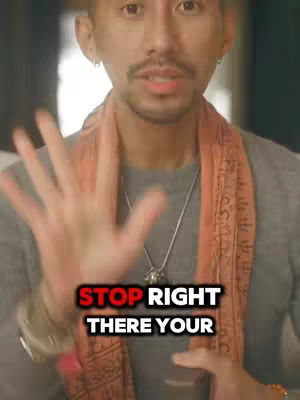 A man with dark hair and a mustache is the focus. He is wearing a gray shirt, an orange scarf, and has a silver necklace. The image has text overlayed with 'STOP RIGHT THERE YOUR' over a red background.