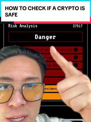 A selfie-style shot featuring a man with glasses pointing towards a screen displaying a risk analysis of a crypto and a warning labeled 'Danger'. The man is in the foreground with the screen acting as a backdrop.