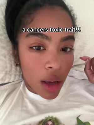 A close-up shot of a woman lying in bed, looking towards the camera with a slightly open mouth. The woman has dark hair, is fair-skinned, and wears a white t-shirt. The bedclothes are visible, with a pillow behind her. Text overlays her head, composed of a white font.