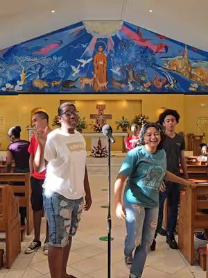 The cover image shows a group of young people during a live event, with a large, colorful mural in the background and a microphone set up in front of them. The composition centers on a teenage boy and girl; they are the focal points, while other young people are visible in the background.
