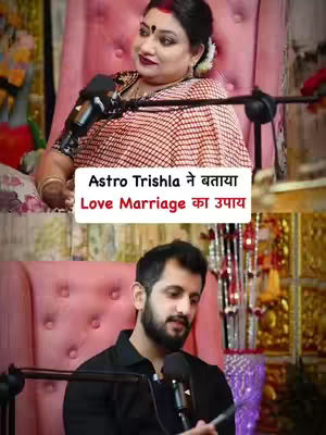 The cover image presents a split-screen composition featuring two individuals. The top half shows a woman seated in a pink armchair, with a microphone positioned in front of her. Beneath, is a man in a black shirt positioned similarly. Both are presented against a soft, blurred background which may indicate a studio setting. A text overlay at the center reads, "Astro Trishla ने बताया Love Marriage का उपाय", indicating the topic of the video.