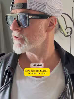 A medium shot from the chest up shows a man facing slightly to the left. He wears sunglasses, a backwards baseball cap, and a black leather jacket over a white t-shirt. A bright yellow rectangle with the words "New moon in Taurus Sunday Apr. 27th" is overlaid on his chest.