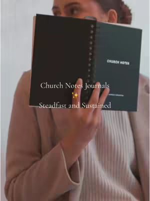 A woman holds an open journal, partially obscuring her face. The journal is black with white text. Text overlays on the image say, "Church Notes Journals," and "Steadfast and Sustained." A golden star-shaped graphic sits between the text overlays. The woman is wearing a muted pink blazer and a light-colored top, with hints of a room in the background.
