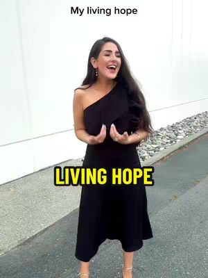 A woman in a black dress stands outdoors, arms raised as if in praise, with text overlays indicating the subject is about 'Living Hope'. The background features a white wall and a sidewalk.