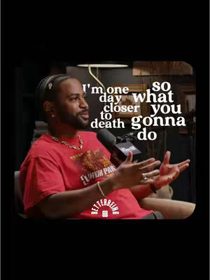 The image shows a man with a beard and a red t-shirt on a dark background. Text is overlayed on the image.