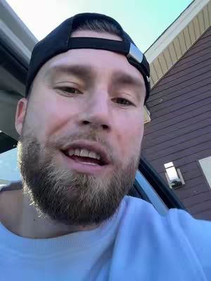 The cover image is a selfie taken by a man inside a car. The man is looking at the camera with a focused expression. He is wearing a black baseball cap and a white t-shirt. The background is a residential street scene.