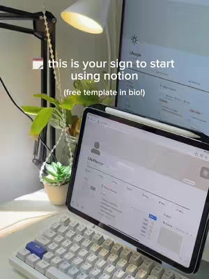 The image showcases a well-lit desk setup with a tablet and a keyboard. A white mechanical keyboard, a tablet displaying a digital planner interface, a tall plant, a desk lamp, and a computer monitor are visible. The background subtly reveals the setting with organized items on the desk, with the focus on the tech and the overall arrangement. The text overlay is at the top.