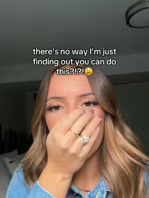 The cover image shows a close-up of a person's face. The person has long, light brown hair, heavy eye makeup, and is wearing a blue jean jacket. Their right hand is covering their mouth. The text overlay states, "there's no way I'm just finding out you can do this?!?!" and an emoji.