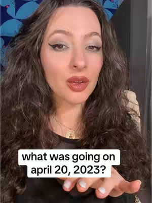 A woman with long, wavy dark brown hair and dark eyeliner looks directly at the viewer. She has a slightly open mouth and is holding out her right hand with the palm facing up. Overlaid at the bottom of the image, centered, is a white rectangular textbox with the text: what was going on april 20, 2023?