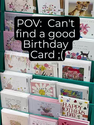 The image shows a shelf filled with greeting cards, primarily for Mother's Day and birthdays. The cards are arranged in rows and columns, with various designs and colors. A black text box, overlaid in the center of the image, reads 'POV: Can't find a good Birthday Card ;('. The overall composition is a close-up shot, highlighting the variety of cards and the user's perspective.