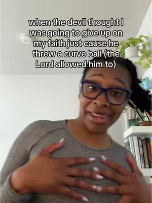 A woman with dark hair and glasses looks towards the camera with a slightly surprised expression, hands on her chest. Overlaid text in a rounded box is white, near the top. The background is a white wall with part of a shelf.