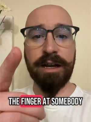 A bald man with glasses and a beard points his finger towards the camera. Text overlayed on the bottom reads "THE FINGER AT SOMEBODY". The background is a plain wall.