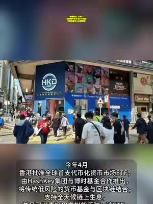 The image shows a bustling city street scene with a multi-story building featuring signage for 'HKD' in a blue and white circle. A text overlay in yellow at the top indicates an announcement. The building's exterior has windows and panels adorned with images, with people visible walking on the street in the foreground and a text box at the bottom of the image.