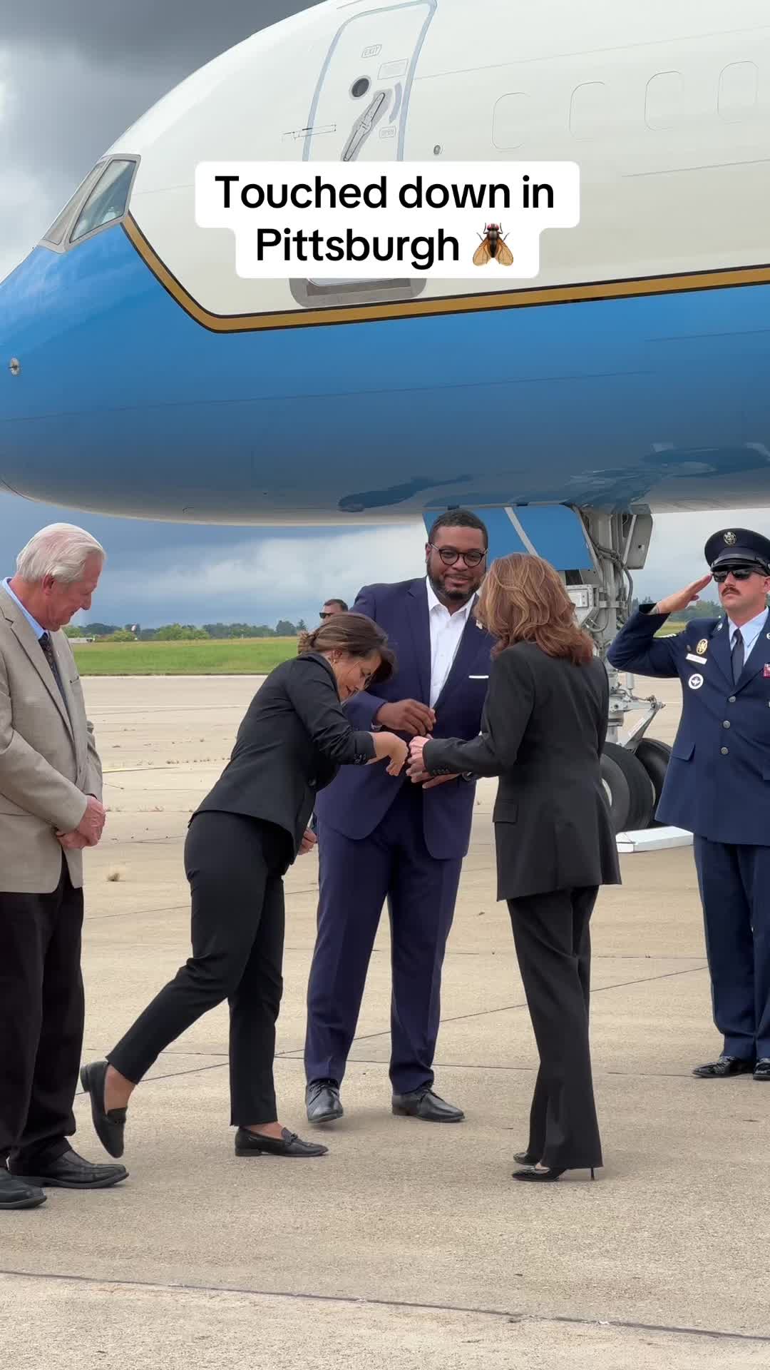 The cover image shows a group of people, likely at an airport, standing on a tarmac in front of an airplane. Text overlayed on the image reads \"Touched down in Pittsburgh\" with a bee icon. The scene is brightly lit with a blue and white airplane in the background.