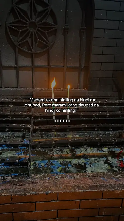 A low-angle shot of two candles burning in front of a dark, ornate background. Below candles is a long shelf with a text overlay.