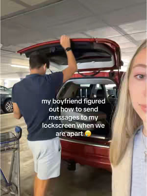 The cover image shows a couple in what appears to be a parking garage. A man, viewed from the back, is lifting the hatchback of a red SUV. A woman with long blonde hair and holding a phone is visible on the right, facing the camera.