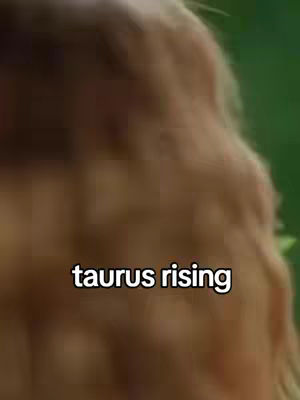 An out-of-focus image with a blurred, brownish background and foreground. The words "taurus rising" in white text are overlaid on the image.