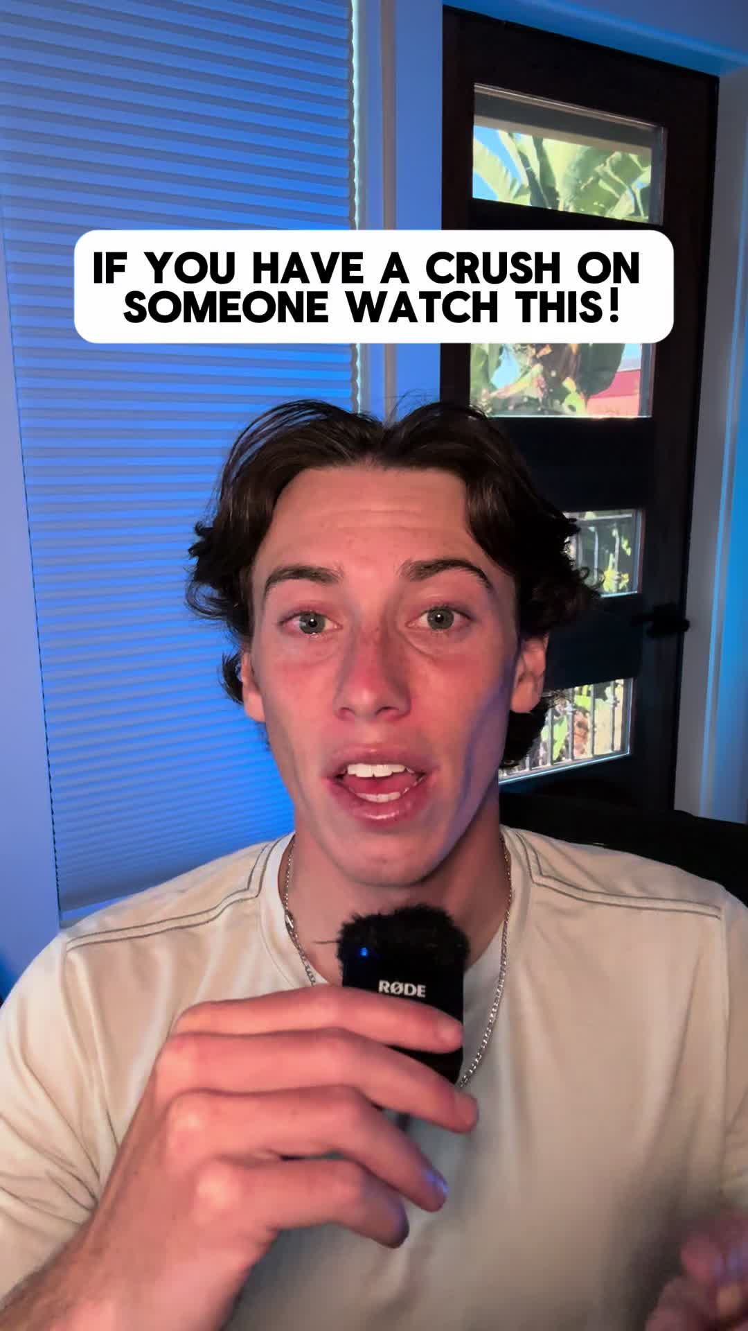 The cover image features a young man speaking into a microphone, with text overlay in a white rounded rectangle. The background includes blue vertical blinds, and a glimpse of a room with black doors is visible.