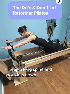 A woman is positioned on a Pilates reformer machine, angled to the left, performing an exercise. She's wearing a black athletic outfit. Above her, in a purple rectangle, the text 'The Do's & Don'ts of Reformer Pilates' is displayed. Below, text provides instruction: '- Keep a long spine and shoulders down' against a wooden floor background. The setup suggests a tutorial.