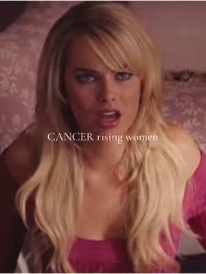 The cover image shows a close-up of a woman with blonde hair looking up and slightly to the side, with an open mouth as if she is speaking. The background is blurred, with a pinkish-purple color tone. The text "CANCER rising women" is overlaid on the image.