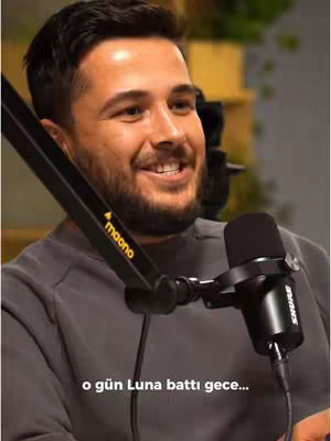A smiling man with short dark hair and a beard, wearing a gray shirt, is positioned with a microphone in front of him. The microphone is black and connected to a black stand, with the brand 'shure' visible. The man is set against a blurred background, with the hook text at the bottom of the image.