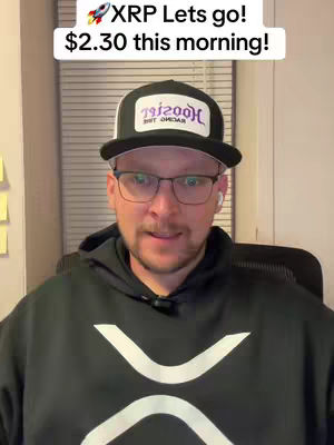 A man with glasses and a baseball cap is centered in the frame, set against a backdrop of window blinds. The man is wearing a black hoodie with a white logo. A white text box at the top of the image reads: "XRP Lets go! $2.30 this morning!"