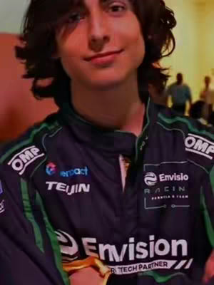 The cover image features a young man with dark, wavy hair, wearing a dark racing suit with green and white accents. He is smiling slightly, and the background appears to be a blurred indoor setting. Sponsor logos and branding are visible on the racing suit.