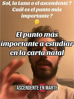 A selfie-style image featuring a man with a beard and short, curly hair, taken from the chest up. The image includes overlaid text in a bold, sans-serif font, discussing astrology concepts such as the sun, moon, and ascendant signs, and their significance in a natal chart. The top text asks a question, with another line emphasizing the importance of studying a birth chart. The background appears to be a neutral, possibly indoor setting with a soft ambient light.