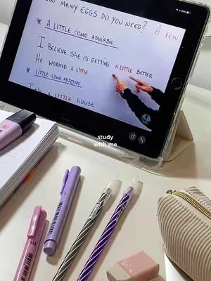 The cover image shows a setup for studying. An open tablet displays notes with handwritten text in a foreign language, likely Spanish. Pens, highlighters, and a pencil case surround the tablet on a white surface. The lighting is bright, with soft shadows, suggesting a well-lit workspace.