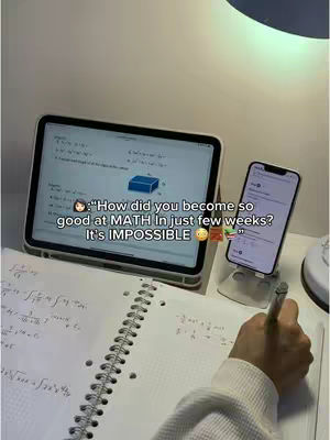 The image is a top-down shot of a workspace, featuring an open notebook with mathematical equations, an open tablet displaying a math problem, and a smartphone propped up. The foreground includes a hand holding a pen, suggesting someone working on the math problems. The lighting appears to be from a lamp above, casting soft shadows. Text overlays the image with a dialogue bubble, and the color scheme is muted with white, black, and touches of color from the screens.