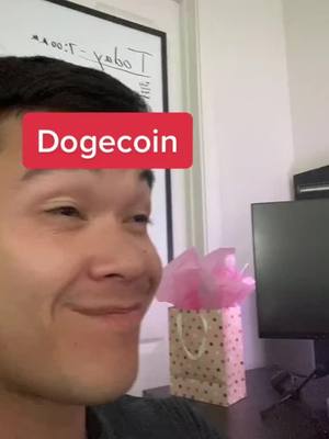 A man with dark hair smiles and looks to the side, with overlay text reading 'Dogecoin' in a red box above his head. Behind him are a white board and a computer monitor.