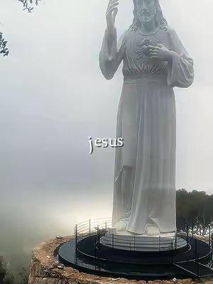 The cover image features a large, white statue of Jesus Christ on a rocky outcrop with the sky in the background. The word "jesus" is overlaid on the image in a simple white font. The statue is a full-body depiction and seems to be reaching upwards with one hand and holding the other near the heart, the setting is foggy, giving an ethereal look.
