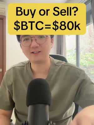 A man with glasses and a casual olive green shirt is centered in the frame, a black microphone positioned below his face. A yellow rectangular text overlay hovers above his head, displaying the question 'Buy or Sell?' followed by '$BTC=$80k'. The composition implies a discussion about Bitcoin.