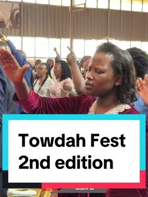 A candid shot capturing a group of people in an enclosed space. The main focus is a woman with dark hair wearing a red top, facing slightly right with her eyes closed and right arm raised. In the foreground, a white rectangle with black text that reads 'Towdah Fest' and '2nd edition'.