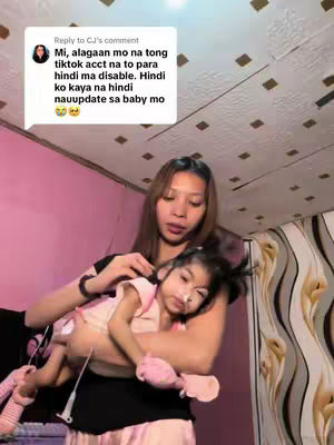 A woman holds a young child in her arms. The woman is wearing a black shirt, and the child is wearing a pink outfit and has medical equipment attached. A speech bubble overlay with text is visible at the top left.