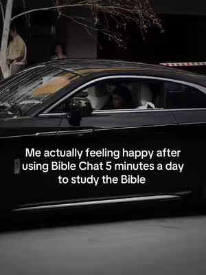 A black car, possibly a Rolls-Royce, is parked on a street. The main focus is on the car's side profile with a person visible inside. The background includes street elements and possibly other people. Text overlayed on the image reads: "Me actually feeling happy after using Bible Chat 5 minutes a day to study the Bible."