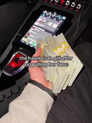 A hand holding a large stack of cash, with a car interior visible in the background, including a touchscreen display. Text overlay at the bottom.