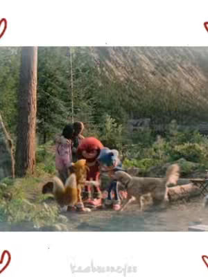 The image shows a scene in a forest with several characters from Sonic the Hedgehog, including Sonic, Knuckles, and Tails, along with human characters, engaged in a scene with natural lighting and a sense of camaraderie and adventure.