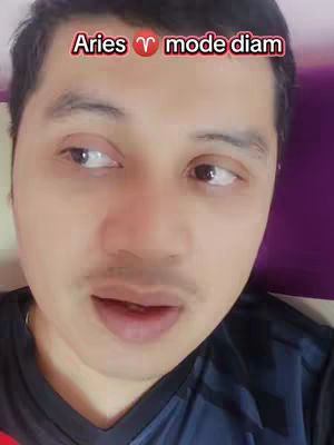 A close-up shot of a man's face, angled slightly from the side. He has dark hair and a short mustache. A text overlay at the top reads, "Aries mode diam." The background is out of focus, with a hint of purple.