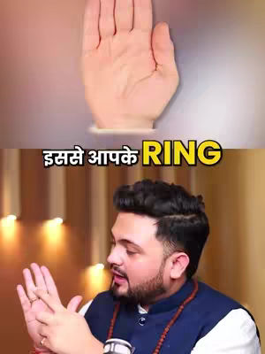 The image is segmented into two parts. The top section shows a close-up of a hand, palm facing upwards and inwards. The skin tone is light. The background is blurred, creating a soft ambience. The bottom section features a man with dark, neatly styled hair and a trimmed beard. He is facing towards the left and looking downwards. The man is wearing a combination of a white shirt underneath a dark blue vest, he also wear multiple jewelry. The background is lightly blurred with lights.