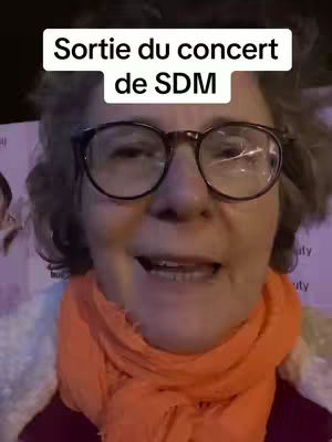 A woman with glasses smiles and speaks. Text overlays on the image.