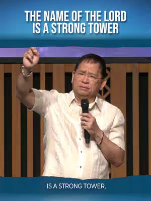 A man in a light-colored shirt stands in front of wooden panels. Text overlays the image in the top and bottom, with the man appearing to be giving a speech and holding a microphone.