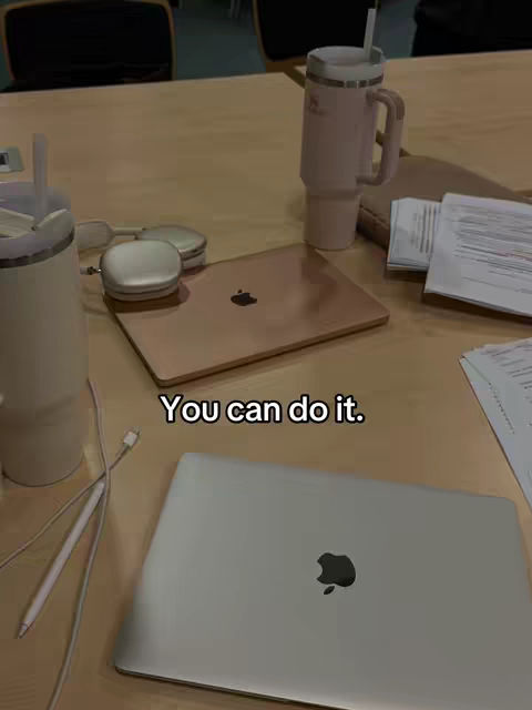 The image shows a wooden table with a laptop, a mug, headphones, a pen, and papers. The text overlay reads: You can do it.