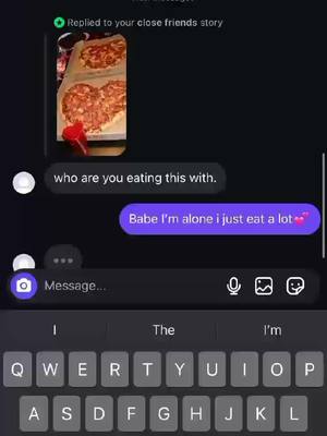 A screenshot of a phone conversation. The top half shows a photo of two heart-shaped pizzas on a tray. Below are text bubbles: a gray one from the user asking "who are you eating this with." and a purple one with the reply "Babe I'm alone i just eat a lot ❤️". The phone's keyboard is partially visible at the bottom.