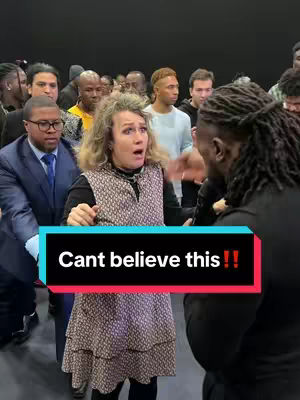 The cover image depicts a group of people in a room with a woman in the center, looking shocked with her mouth open. A text overlay saying 'Cant believe this !!' is placed prominently at the bottom. The people in the background are blurred, focusing attention on the woman. The color scheme is muted with some areas of stronger illumination; the lighting emphasizes the woman's shocked expression.