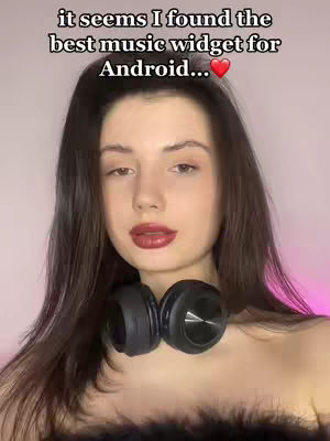 A woman with long dark hair is looking at the camera. Covering her neck is a black fluffy accessory and a black pair of headphones. Text overlays the woman's head.