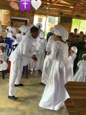 The cover image shows a candid moment within what appears to be a church setting. Several individuals, predominantly dressed in white garments, are captured in medium shots, seemingly engaged in a ceremony or a group activity. In the foreground, two figures are central to the composition. One, a man in white, is leaning towards a woman who is angled slightly to the right. Behind them a crowd watches the interaction. The environment suggests a wooden structure with natural light and high ceilings. The scene is filled with an atmosphere of community.